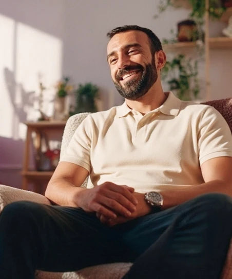 Мужчина с бородой сидит на диване и улыбается