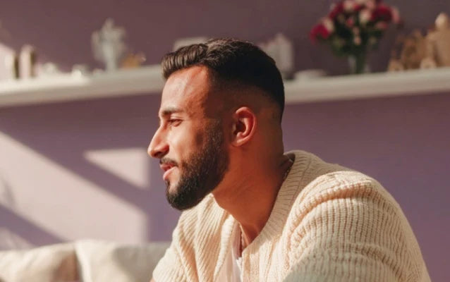 Мужчина сидит боком, разговаривает и улыбается